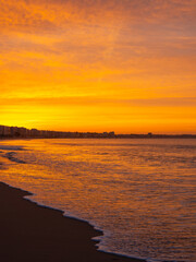 Amazing view of a fiery sunrise with multicolored clouds. Sea waves along the seashore at sunrise. Morning time. Ocean view. La Baule-Escoublac, France