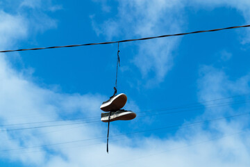 Shoes hanging on wires. Pair of an old sneakers hanging from a power line