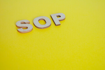 SOP wooden letters representing Standard Operating Procedures on yellow background