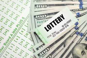 Green lottery tickets and US money bills on blank with numbers for playing lottery close up