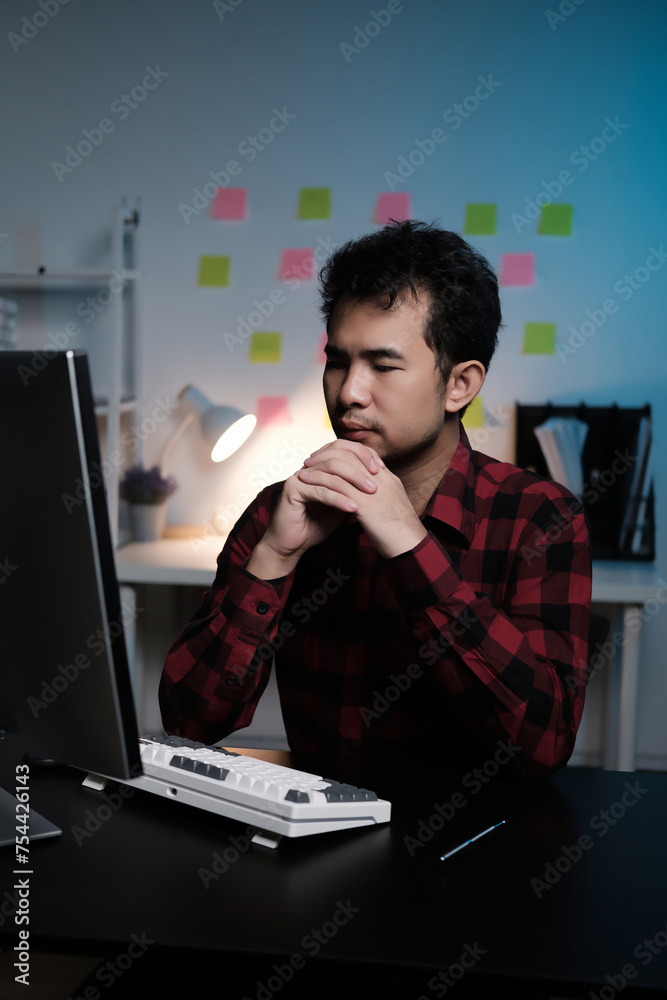 Poster A man is sitting at a desk with a computer monitor and keyboard in front of him