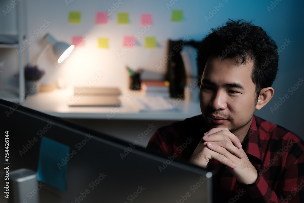 Poster A man is sitting in front of a computer monitor