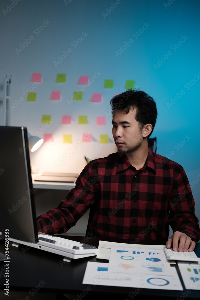 Poster A man is sitting at a desk with a computer monitor and a keyboard