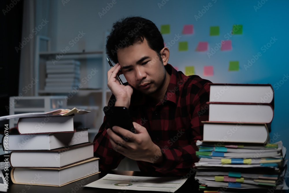 Poster a man is sitting at a desk with a stack of books and a cell phone