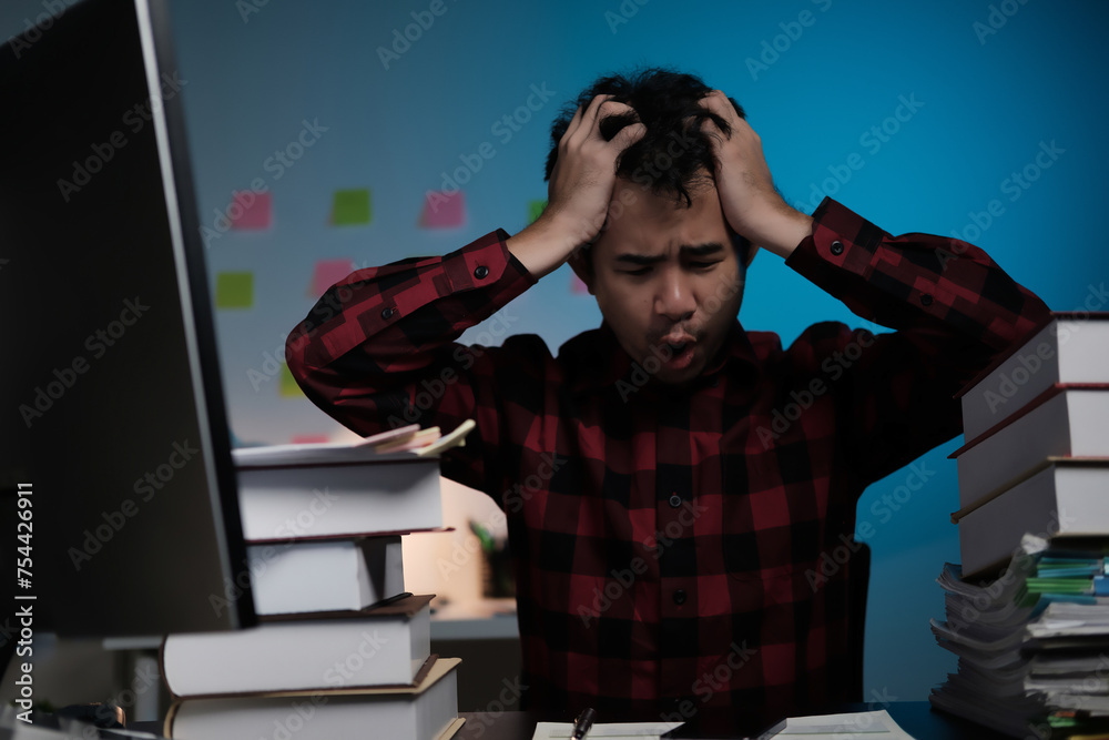 Poster A man is sitting at a desk with a computer monitor and a stack of books