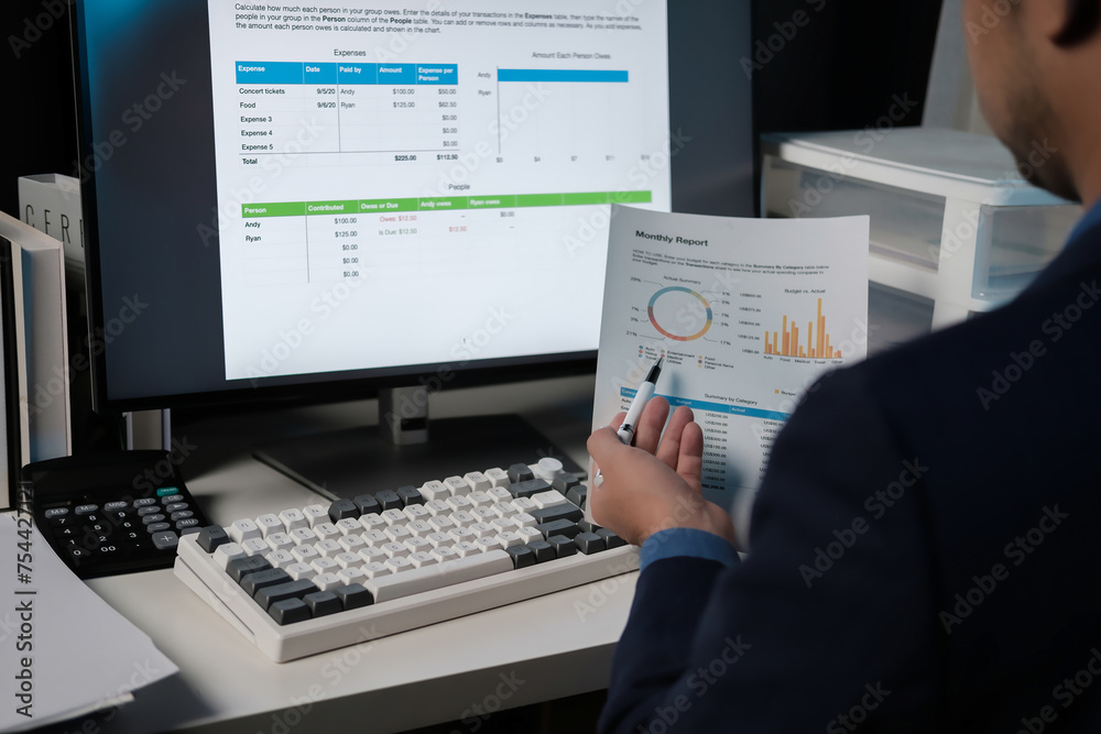 Poster A man is sitting at a desk with a computer monitor and a piece of paper