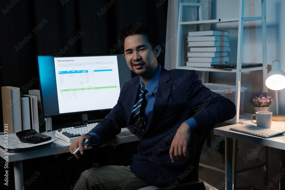 Poster A man in a suit is sitting at a desk with a computer monitor in front of him