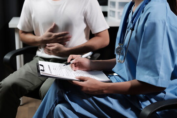 A doctor is writing on a clipboard while a patient sits in a chair