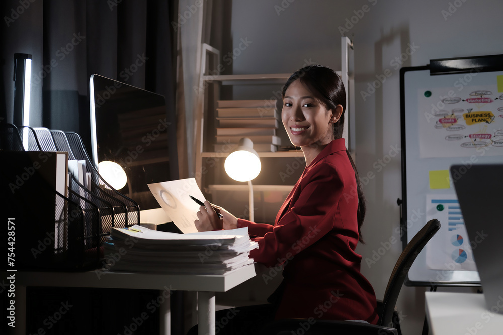 Poster A woman is sitting at a desk with a computer monitor and a stack of papers