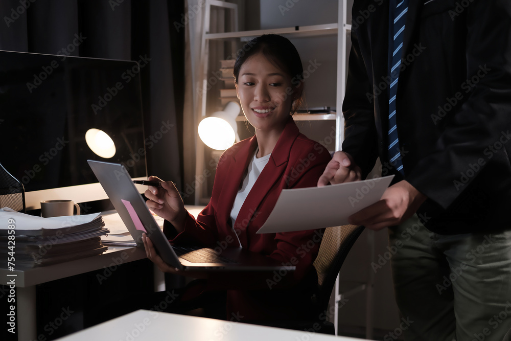 Poster a woman in a red jacket is sitting at a desk with a laptop and a stack of papers