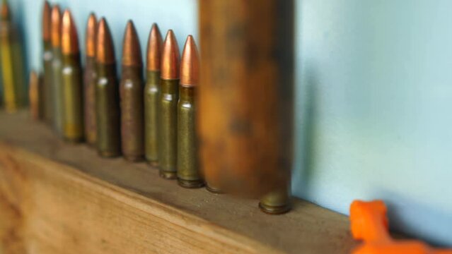 A panning shot of a row of bullets stacked on a shelf at a gun range in slow motion.