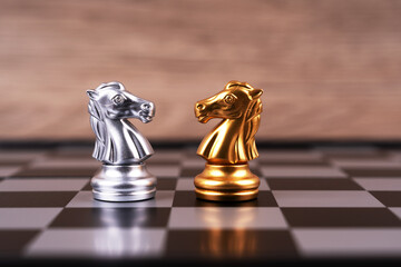 Motivational business and management concept. A pair of silver and gold chess knights facing each...