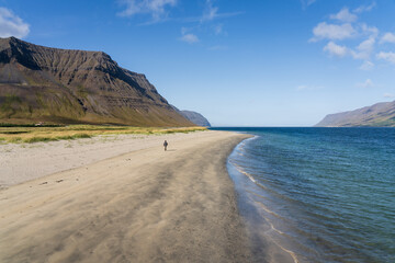 Holtsfjara - Girl walking alone on sandy beach close to Önundarfjörður Pier in Westfjords, Iceland. Beautiful nature and travel destination