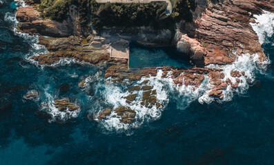 Aerial drone view of Blue Pool in Bermagui during sunrise sunset with blue sky and reflection. New South Wales, Australia