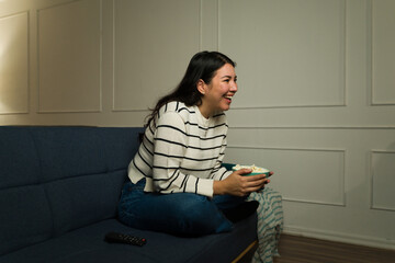Cheerful woman smiling enjoying watching a movie at home