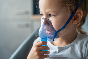 Close up view of little girl are sitting and holding a nebulizer mask leaning against the face, airway treatment concept