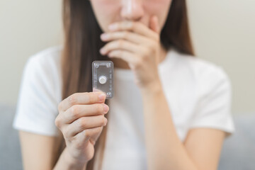 Emergency contraception and pregnancy concept asian young woman hand holding birth control pills, hormonal oral contraceptive medicine at home, take pharmaceutical to prevention virus sex disease.