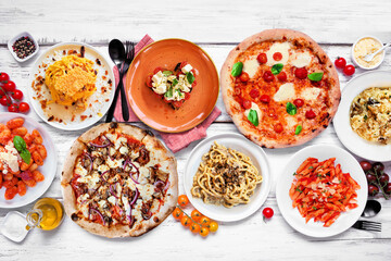 Delicious Italian food table scene. Variety of pizzas, pastas, gnocchi, risotto and bruschetta. Overhead view on a white wood background. - 754469119