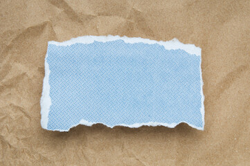 Blue paper  piece with ripped edge on brown paper background