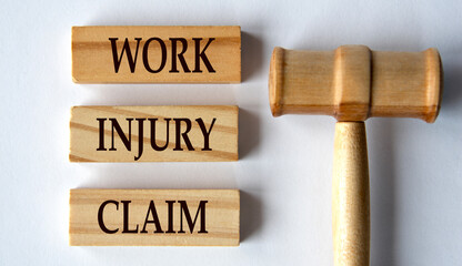 WORK INJURY CLAIM - words on wooden blocks on a white background with a judge's gavel.