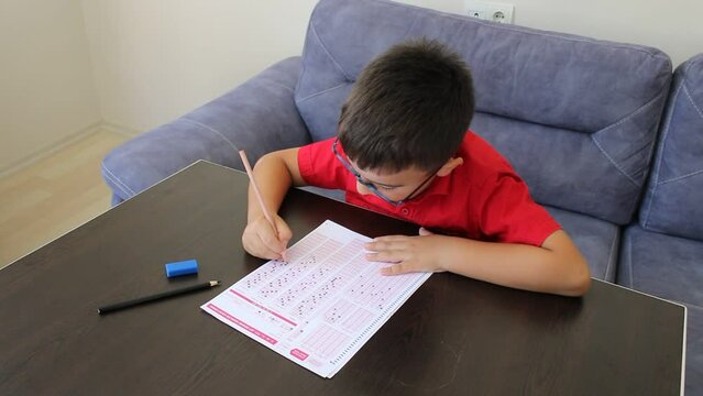 Male junior student filling out exam answer key

