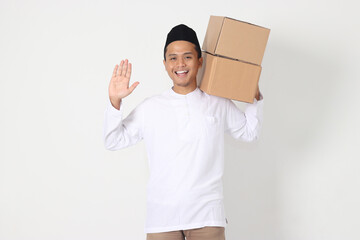Portrait of excited Asian muslim man in koko shirt with peci carrying cardboard box while saying...