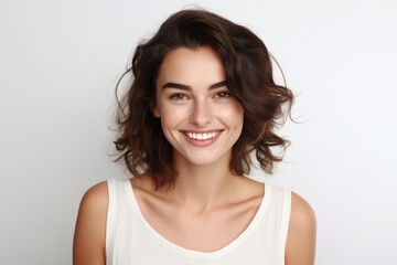 Fototapeta premium A woman wearing a white tank top smiling at the camera. Perfect for lifestyle or fashion concepts