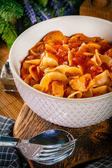 Pieces of chicken with noodle in tomato and herb sauce.