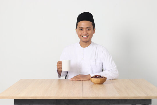 Portrait of serious Asian muslim man drinking a glass of water during sahur and breaking fast. Culture and tradition on Ramadan month. Isolated image on white background