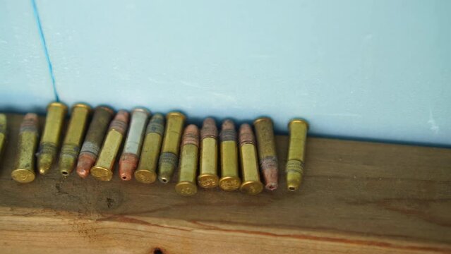 A panning shot of a row of bullets stacked on a shelf at a gun range in slow motion.