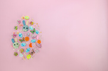 Creative Easter egg made with colorful candies, wooden buttons, flowers on pastel pink background. Flat lay Easter concept