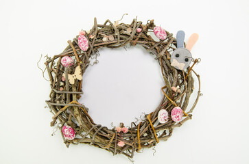 Wreath of branches on white background with colorful easter egg candies, flowers and bunny figures. Easter concept.