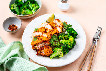 Crispy chicken cutlet with katsu sauce, with white rice and broccoli on a stone table.
