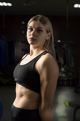 Fototapeta na wymiar Portrait of a young beautiful blonde sportswoman in the gym.