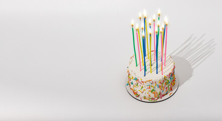 Birthday bento cake with high tall candles, fire light. Banner background, copy space for text