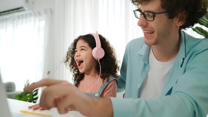 Caucasian dad put headphones on daughter while girl learning code. Father take care schoolgirl...