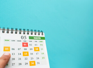 Dedo apuntando el 5 de mayo en el calendario 2024 sobre un fondo azul 