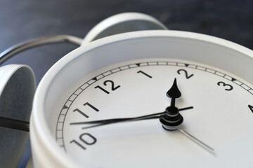 A classic white alarm clock timepiece at an angle - concept for time change, daylight savings time