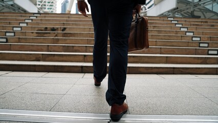 Close up of businessman leg walking up stairs surrounded by urban view. Back view of ambitious...