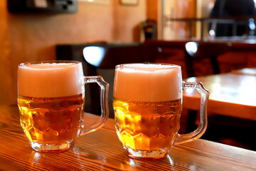 A glass of beer against background of blurred image of cafe, bar, restaurant, close-up. A foggy mug, glass of cold beer.