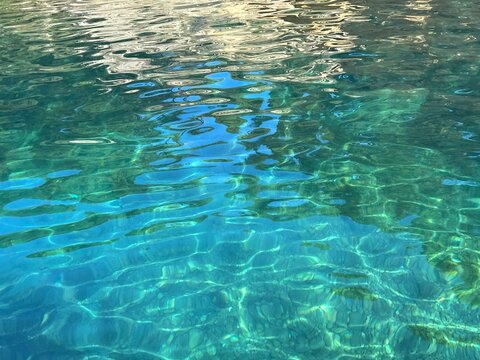 Turquoise green clear sea water with pebbles on seabed 
