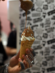 hands of a person preparing a cream ice cream with dulce de leche in a cone