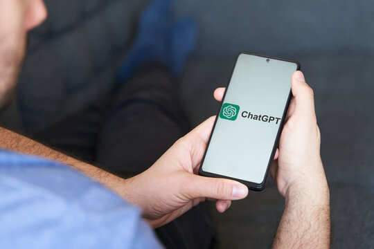 Young male in sofa using ChatGPT app in  smartphone
