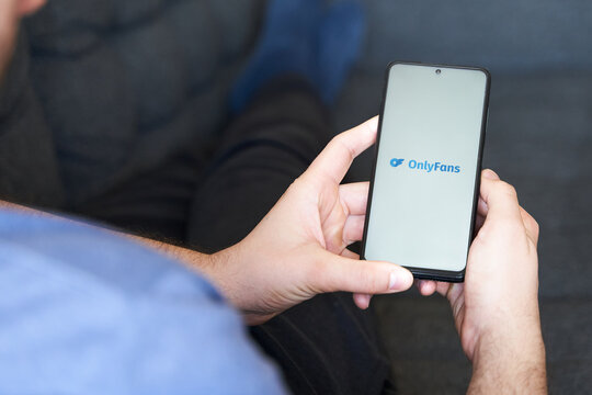 Young male in sofa using Onlyfans app in  smartphone