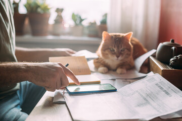 Close-up of men's hands with a calculator and utility bills.