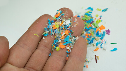 Close-up on many microplastic particles in a human hand. Concept of plastic pollution with...