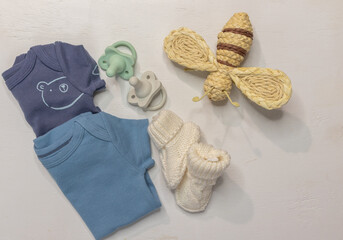 Two blue baby boy onesies, pacifiers and booties on white background with copy space for gender...