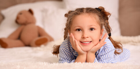 Fototapeta premium Cute little girl lying in bedroom, closeup