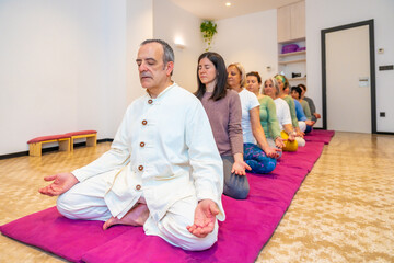 Yoga teacher leading a group of women meditating