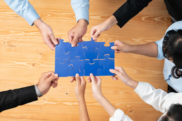 Top view multiethnic business people holding jigsaw pieces and merge them together as effective...